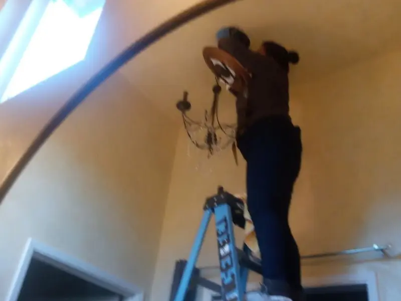 Electrician installing a chandelier in a McKean residence